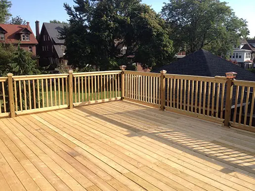 A pressure-treated lumber deck surrounded by a wooden fence.