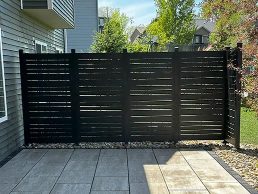 An ornamental fence with narrow horizontal slats adds a decorative element to a stone patio.