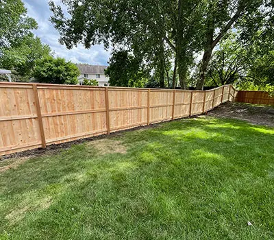 A long wooden fence creates a border around a grassy lawn.