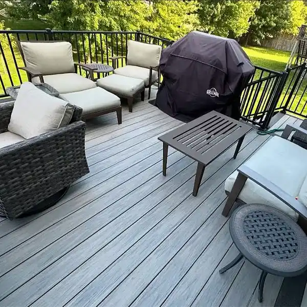The outdoor seating area on a raised deck features chairs, tables, and a grill.